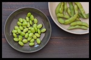 Cooked edamame inside and outside of their pod. These are immature soybeans that are picked before they ripen and harden.