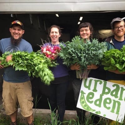 Farmhands and CSA members hold up produce from Urban Eden Farm.